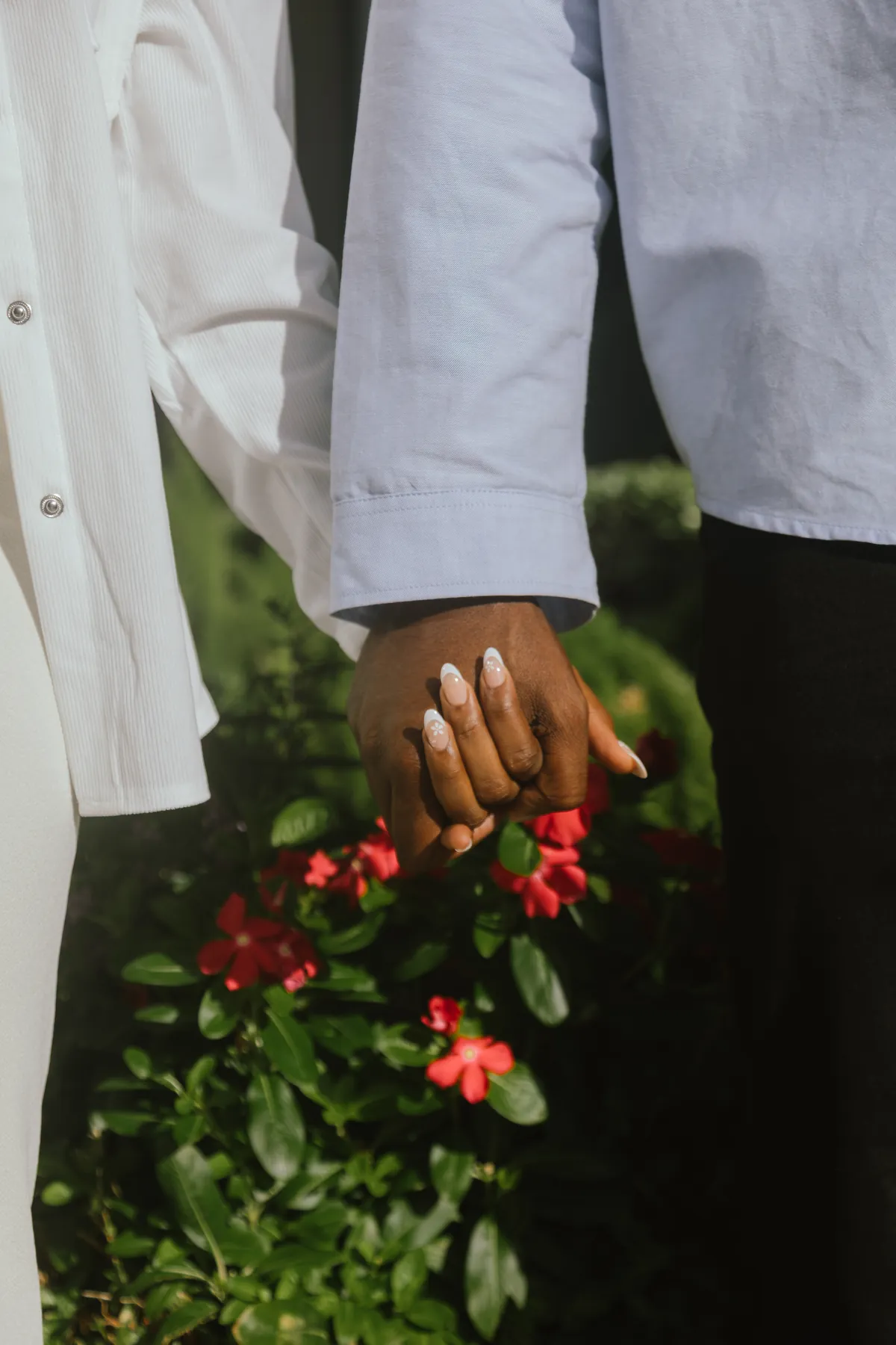 Their hands held together over red flowers